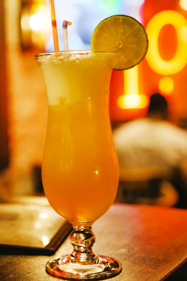 Chilled orange cocktail with a lime slice garnish on a Parisian bar table.