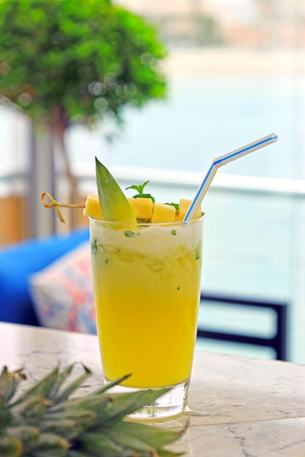 Chilled tropical cocktail with fresh pineapple garnish on a sunny day outdoors, perfect for summer relaxation.