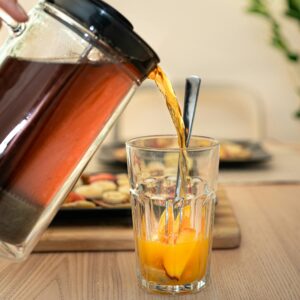 Glass of iced tea poured over fresh fruits in a cozy indoor setting.